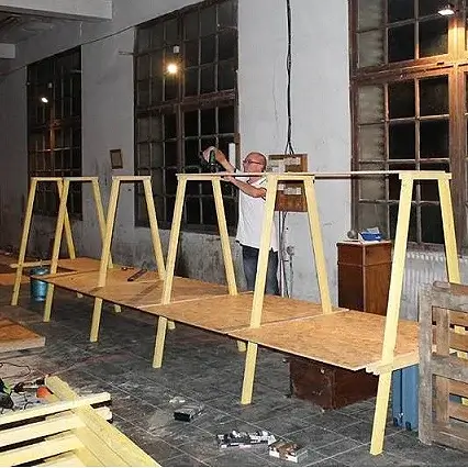 Homme construisant une structure en bois complexe dans un grand espace.