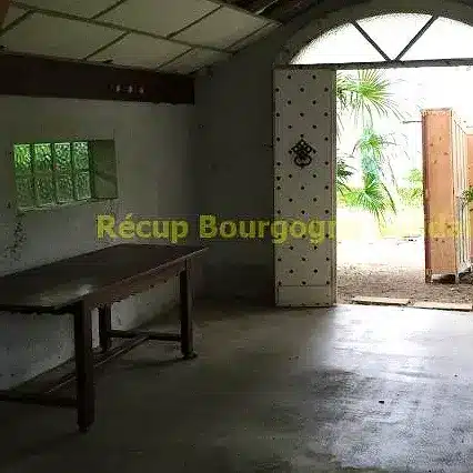 Intérieur d'une pièce avec table et porte ouverte sur l'extérieur.
