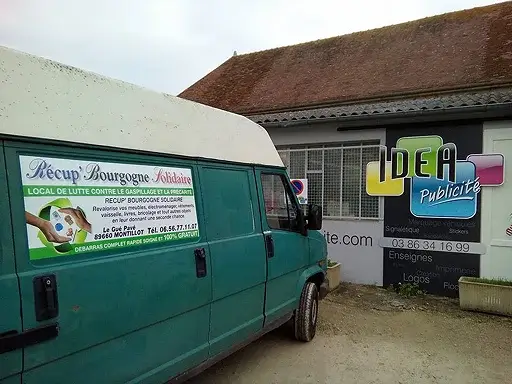 Camionnette verte "Récup' Bourgogne Solidaire" devant un bâtiment "IDEA Publicité".